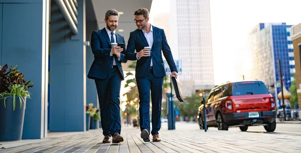 businessmen walk with phone in suit, copy space advertisement. photo of businessmen walk with phone. businessmen walk with phone in the street. businessmen walk with phone outdoor.