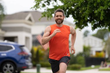 Keyifli bir koşucu caddede koşuyor. Spor koşucusu dışarı koşar. Spor koşucusu antrenman yapmış. Spor koşucusunun fotoğrafı.