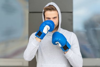 Adam dışarıda boks yapıyor. Boks ve yumruk atma görüntüsü. Erkek boks. Kapüşonlu ve eldivenli adam..