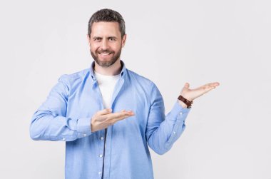 Adam sunar ve reklam sunar. Reklam sunan adam Grey 'de izole edilmiş, kopyalama alanı. Stüdyoda reklamları sunan adam. İnsan fotoğrafı sunar ve reklam sunar..