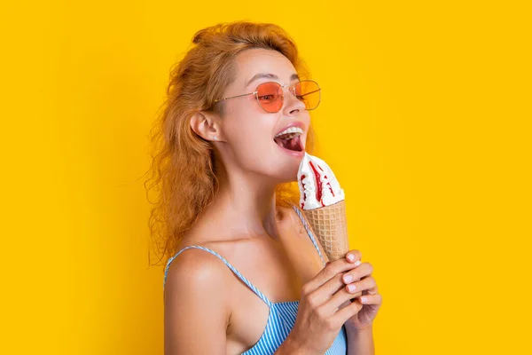 stock image woman eating cone icecream in studio. woman with cone icecream on background. photo of woman with cone icecream at summer. woman with cone icecream isolated on yellow.