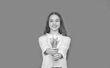 Mutlu çocuk bahar tatili için çiçekleri tutuyor. Turuncu arka planda buketi olan genç bir kız. çocukluk mutluluğu. Kadınlar günü için çiçek hediyeleri. Mart günü. laleli çocuk.