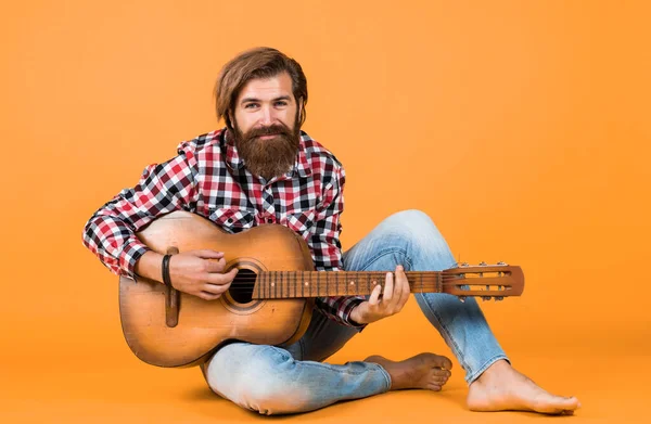 stock image hipster man playing the acoustic guitar. country music style. man wearing checkered shirt and holding guitar. play string musical instrument. professional caucasian musician. guitarist.