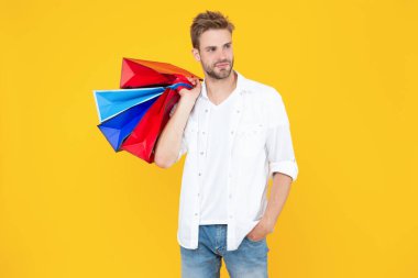 Arka planda alışveriş yapan adam. Alışveriş merkezindeki adamın fotoğrafı. Satıştaki adam sarı yolda izole edilmiş. Stüdyoda alışveriş yapan adam..