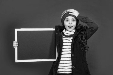 surprised child back to school. announcement and advertisement. winter sales. shocked kid with blackboard in hat. teen girl holding chalkboard with copy space.