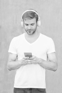 young man choose mp3 music playlist wearing white shirt. photo of man mp3 music playlist in headphones. man open mp3 music playlist. man use mp3 music playlist outside.