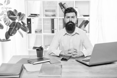 Serious professional man sitting at office desk clasping hands, professionalism.