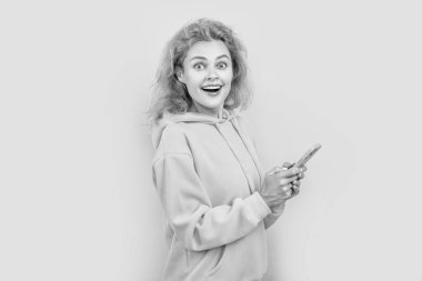 Stüdyoda akıllı telefondan sürpriz kadın sohbeti. Kapüşonlu akıllı telefondan kadın sohbeti fotoğrafı. Kızıl saçlı kadın, renkli arka planda akıllı telefondan sohbet ediyor. Akıllı telefondaki kadın sohbeti mavi arka planda izole edildi.