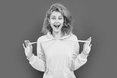 photo of amazed happy stylish woman in hoodie. redhead stylish woman on color background. stylish woman isolated on red background. stylish woman at studio.