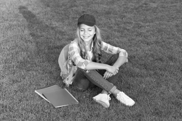 学校の後に草の上に座っている幸せな女の子の生徒 — ストック写真