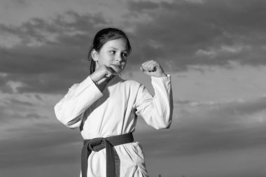 teen girl practicing karate. teen child fighter on sky background. teen kid practicing taekwondo.