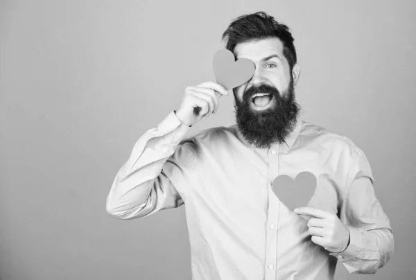 Man bearded hipster with heart valentine card. Celebrate love. Guy attractive with beard and mustache in romantic mood. Feeling love. Dating and relations concept. Falling in love. Happy in love.