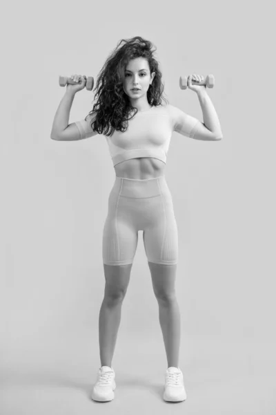 女运动员在演播室里用哑铃做举重运动 女运动员做举重运动 以黄色为背景 健康与体育 — 图库照片