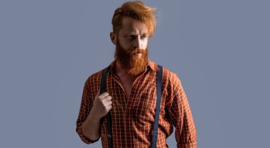 Arka planda pantolon askısı takmış zarif bir hipster. Pantolon askısı takmış hipster bir adamın fotoğrafı. Askılı eski hipster adam gride izole edilmiş. Stüdyoda askılı hipster adam..