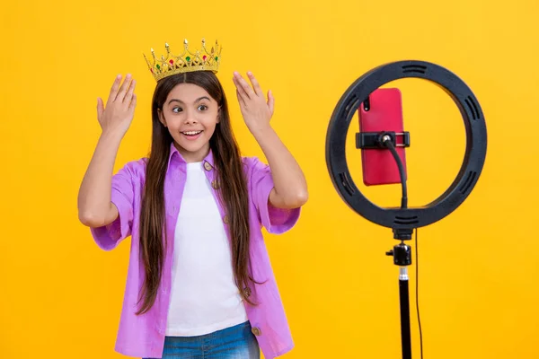 スタジオでクラウンと10代の女の子のインフルエンサーを驚かせました 王冠を背景に10代の少女の影響力 王冠を手にした少女のインフルエンサーの写真です 10代の少女インフルエンサーと王冠は黄色に隔離され — ストック写真