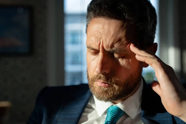 frustrated businessman has migraine at home. frustrated businessman has migraine during the day. frustrated businessman has migraine pain. photo of frustrated businessman has migraine.