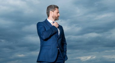 Gökyüzü arka planındaki takım elbiseli adam. Dışarıdaki takım elbiseli adam. Takım elbiseli adam. Takım elbiseli adamın fotoğrafı..