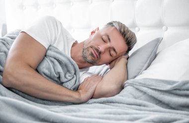 mature guy sleeping in bed. early morning.