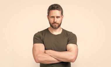 Sakallı, kendine güvenen beyaz bir adamın fotoğrafı. Kirli sakallı beyaz adam tişört giyiyor. Gri arka planda sakallı beyaz bir adam var. Stüdyoda sakalı olan beyaz bir adam..