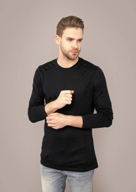 Gri arka planda sakallı genç bir adam. Sakalı olan beyaz bir adam. Tüylü ve sakallı. Stüdyoda sakalı olan adam..