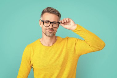 smiling man look in eyewear at studio. man look in eyewear on background. photo of man look in eyewear. man look in eyewear isolated on blue.
