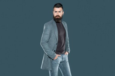 Beyaz sakallı, olgun bir adam gri arka planda rahat giyinir..