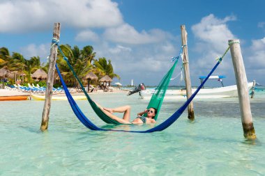 Seksi kadın yaz plajında hamakta dinleniyor. Bir kadının yaz plajında rahatlarken çekilmiş fotoğrafı. Kadınlar yaz kumsalında dinlenir. Kadınlar tatilde yaz kumsalında dinlenirler..