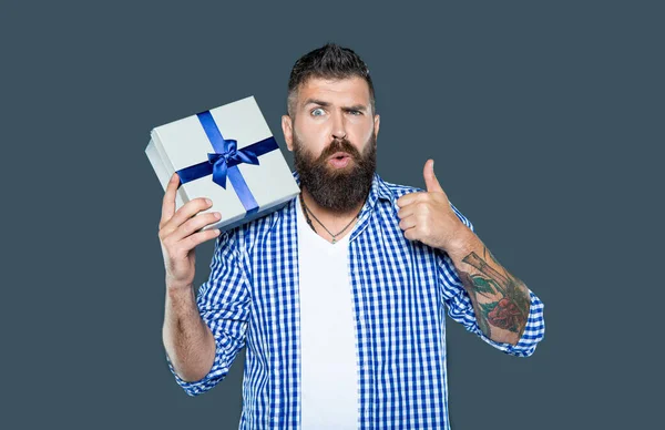 stock image mature bearded guy with present box on grey background. point finger.