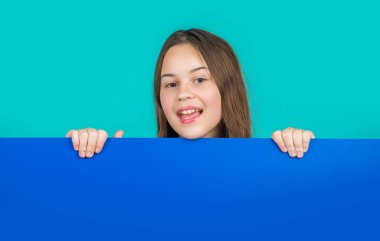 Boş mavi kağıdın arkasında reklam için fotokopi alanı olan neşeli bir çocuk..