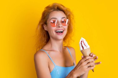 Dondurmalı gülümseyen kadın sarıda izole edilmiş. Stüdyoda dondurmalı bir kadın var. Arka planda dondurma külahı olan kadın. Yazın külahta dondurmalı bir kadının fotoğrafı..