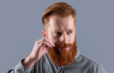 İrlandalı bıyıklı bir adamın portresi. Tıraşsız suratlı sakallı adam. Kızıl sakallı ciddi bir adam Grey 'de izole edilmiş..