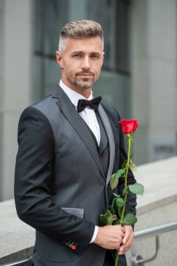 Nişan fikri. Nişanı kutlayan şık smokinli adam. Nişan için gül hediyeli bir adam.