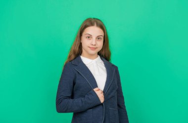 smiling child in school uniform on green background, school.