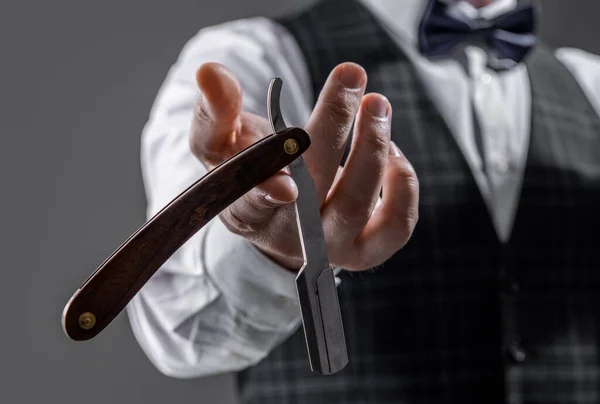 stock image photo with selective focus of barber blade in hand of man. barber man hold blade. barber man with razor blade. man with blade in barber studio.