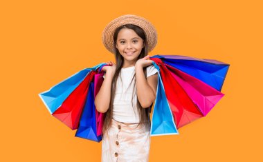 happy teen girl with shopping bags on yellow background.