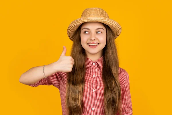 黄色の背景にストローハットの幸せな10代の女の子 親指を上げて — ストック写真