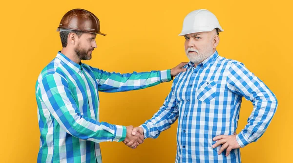 合伙人男人在工作室里握手 与男人握手的背景 男伴握手时戴建筑头盔的照片 男人用黄色隔离的方式握手 — 图库照片