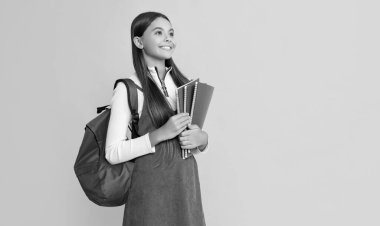 Okul çantası ve çalışma kitabı sarı arka planda olan neşeli çocuk..