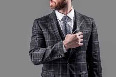 Berber makaslı sakallı adamın fotoğrafı, kopyalama alanı. Berber adam gri arka planda izole edilmiş bir makas tutuyor. Makasla berber adam. Berber stüdyosunda makaslı bir adam..