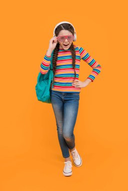 Music school. Teen girl singing along to music after school yellow background, music.
