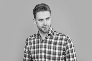 Sıradan tarzda bir adamın yüzü. Stüdyo fotoğrafı. Sakallı beyaz bir adam. Gri arka planda kareli gömlekli yakışıklı bir adam izole edilmiş..