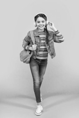 Kulaklıkla müzik dinleyen mutlu genç kız mavi arka plan, eğitim. Okul eğitimi. Resmi olmayan eğitim.