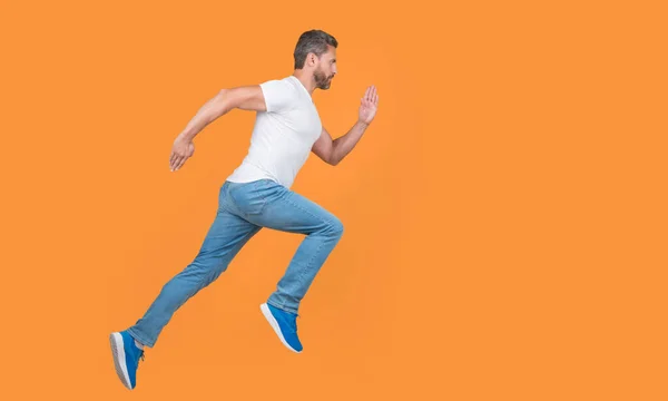 stock image Energetic man running. Guy runner running on studio yellow background. Dynamic running, copy space.