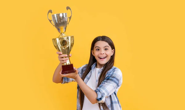 stock image amazed teen champion girl isolated on yellow. teen champion girl in studio. teen champion girl on background. photo of teen champion girl with golden cup.