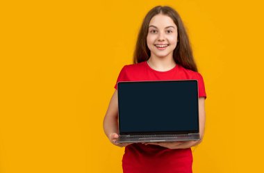 Sarı arka planda dizüstü bilgisayarı olan gülümseyen çocuk.