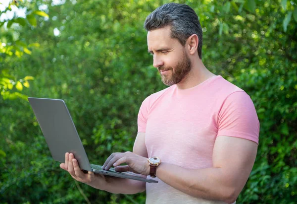 man smile has business online outdoor. man has business online on laptop. photo of man has business online. man has business online.