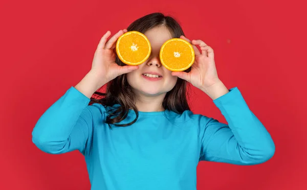 teen kid smile hold orange fruit on purple background.