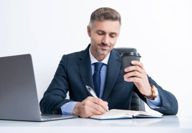 Olgun bir ofis çalışanı iş ofisinde yazı yazıyor ve kahve içiyor..