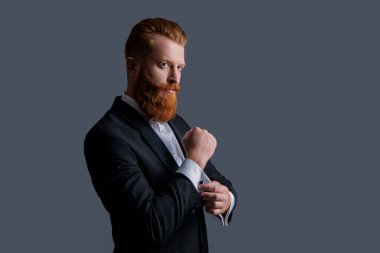 Smokinli yakışıklı sakallı adam gri arka planda izole edilmiş. Smokin giymiş bir adamın stüdyosu. Zarif smokin giyen bir adam. Smokin modası.