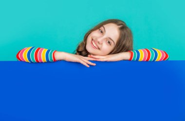 Reklam için fotokopi alanı olan boş mavi kağıdın arkasında pozitif çocuk.